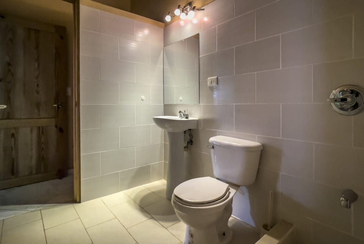 buyDRproperty Bathroom with white tiled walls, sink, and toilet. For Sale 3 Bedroom Villa. Sosua Real Estate