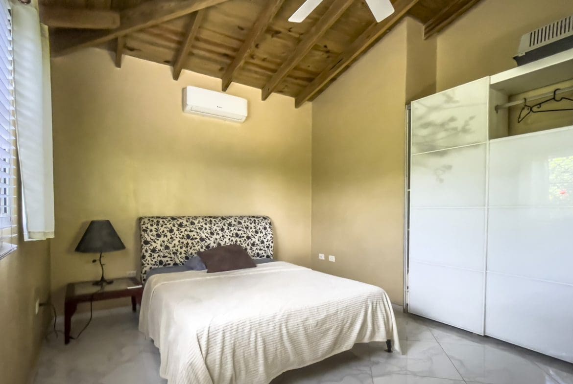 buyDRproperty Bedroom in a 3-bedroom villa for sale, featuring a bed, wardrobe, and exposed wooden ceiling. Sosua Real Estate