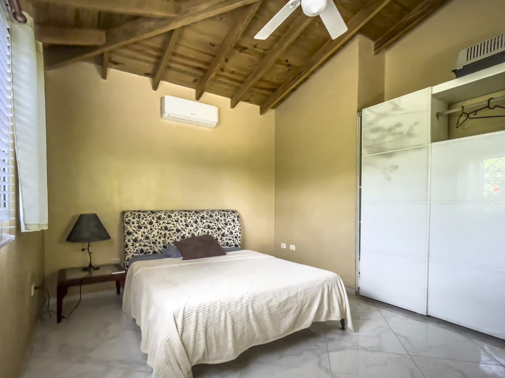buyDRproperty Bedroom in a 3-bedroom villa for sale, featuring a bed, wardrobe, and exposed wooden ceiling. Sosua Real Estate