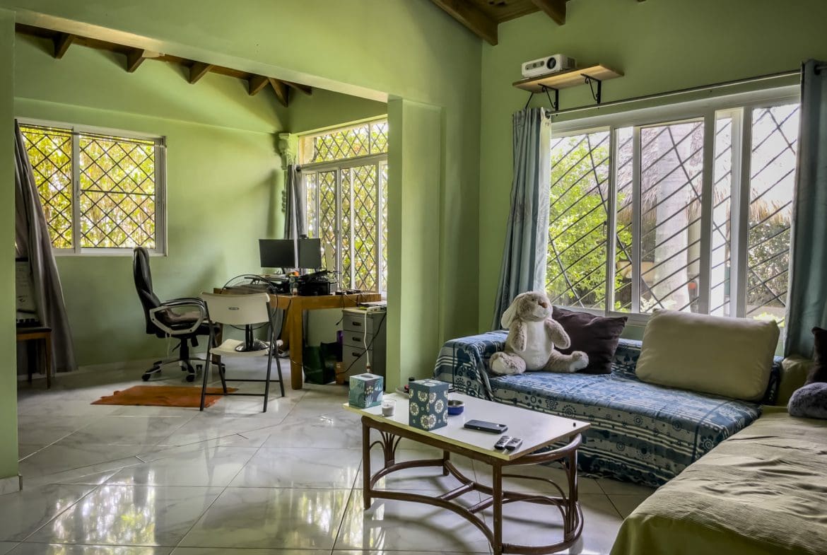 buyDRproperty Living room of a 3-bedroom villa for sale, featuring a sofa, desk, and windows. Sosua Real Estate