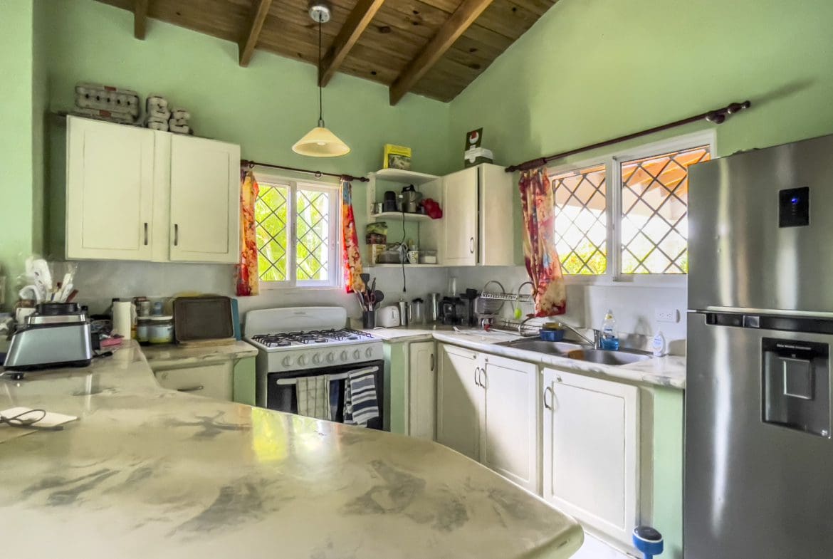 buyDRproperty Kitchen in a 3-bedroom villa for sale featuring white cabinets, a gas stove, and a stainless steel refrigerator. Sosua Real Estate