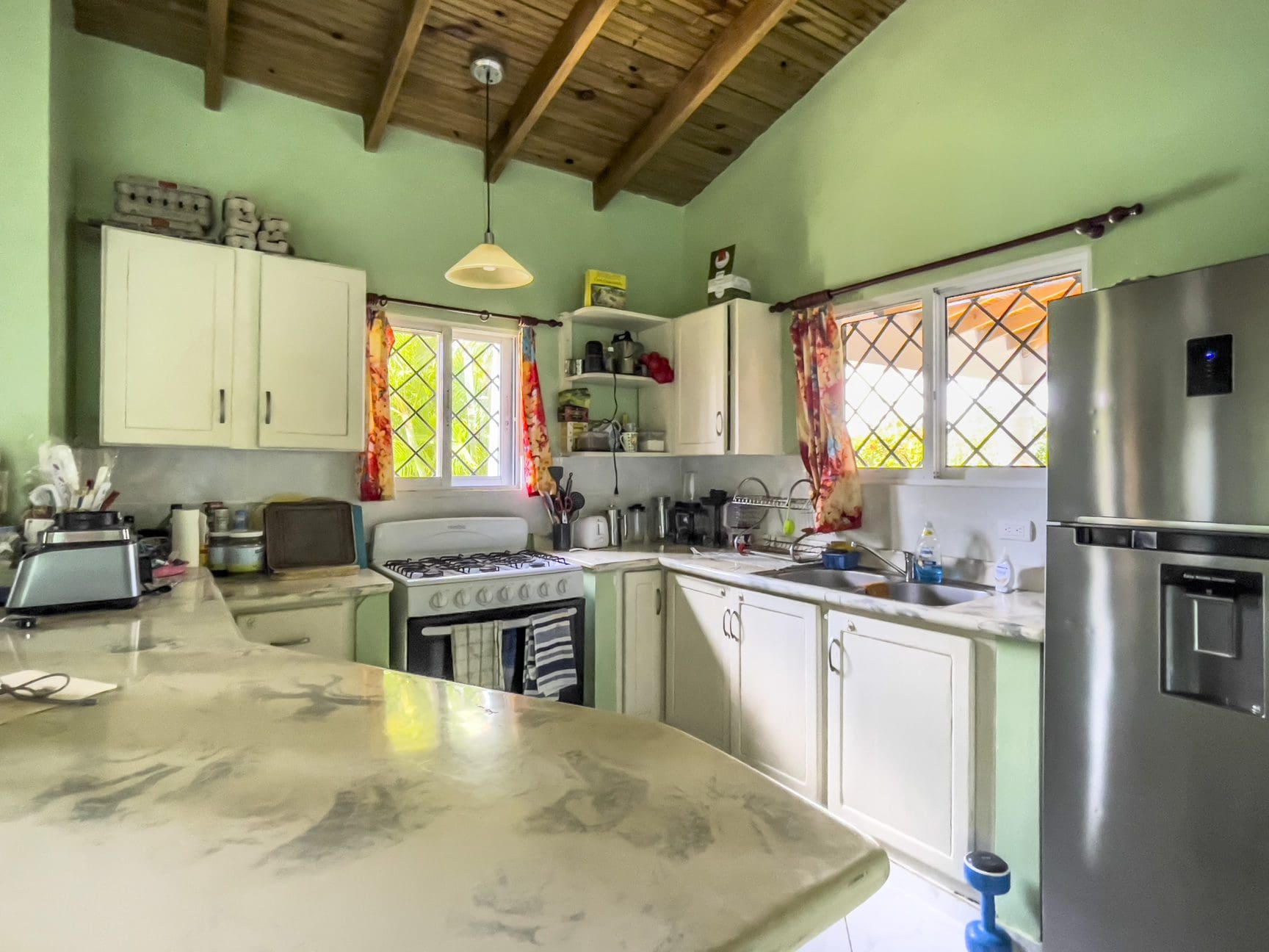 buyDRproperty Kitchen in a 3-bedroom villa for sale featuring white cabinets, a gas stove, and a stainless steel refrigerator. Sosua Real Estate