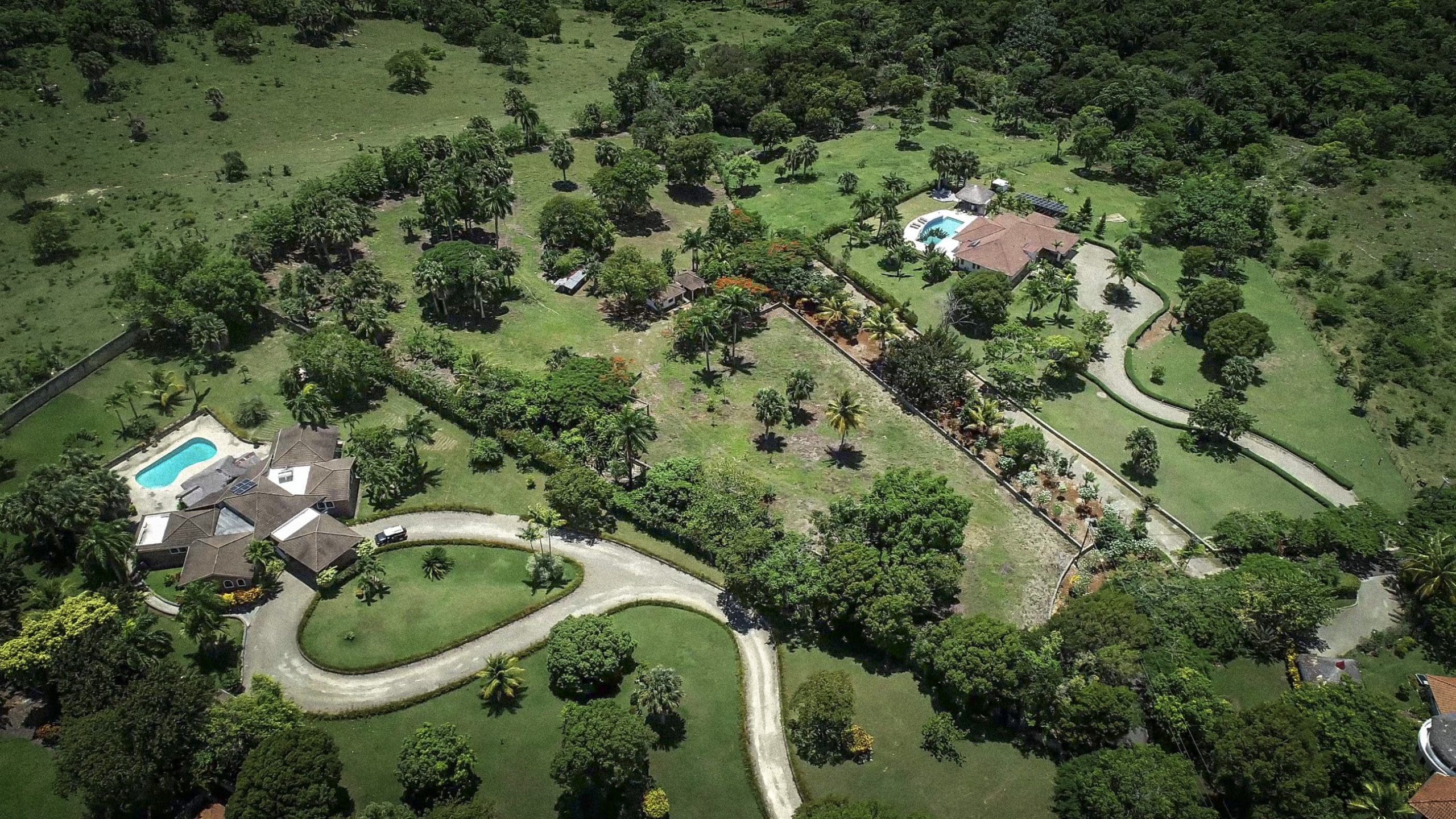 buyDRproperty Aerial view of a beautiful building lot with multiple houses, a pool, and lush landscaping. Sosua Real Estate