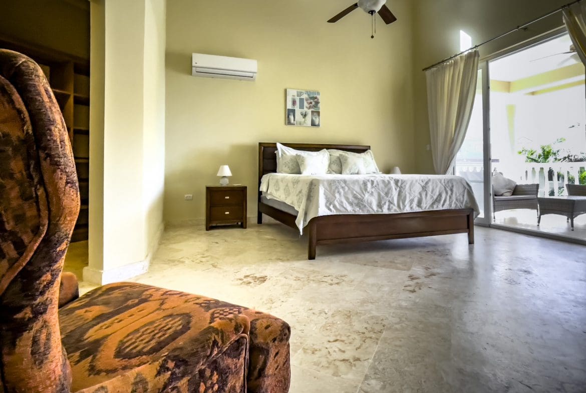buyDRproperty Luxurious bedroom in a stunning 3 bedroom condo with ocean views. Brown bed, chair. Sosua Real Estate