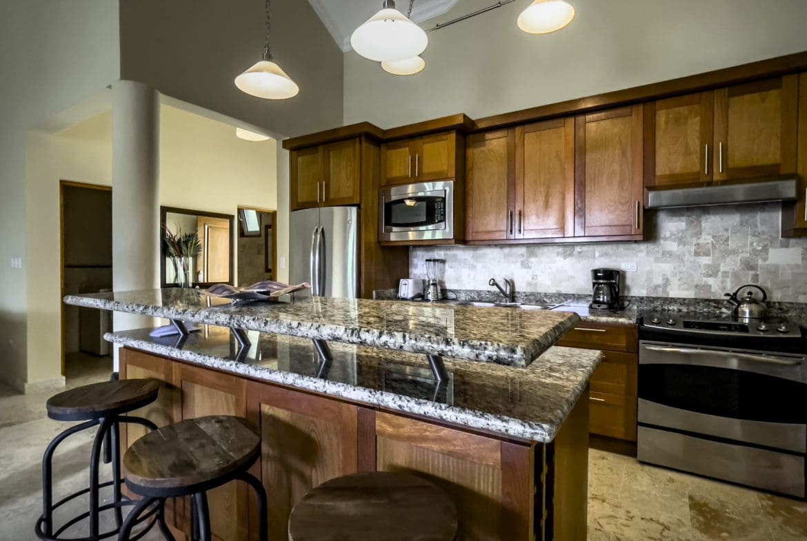 buyDRproperty Stunning 3 Bedroom Condo kitchen with wooden cabinets and a granite countertop island. Sosua Real Estate