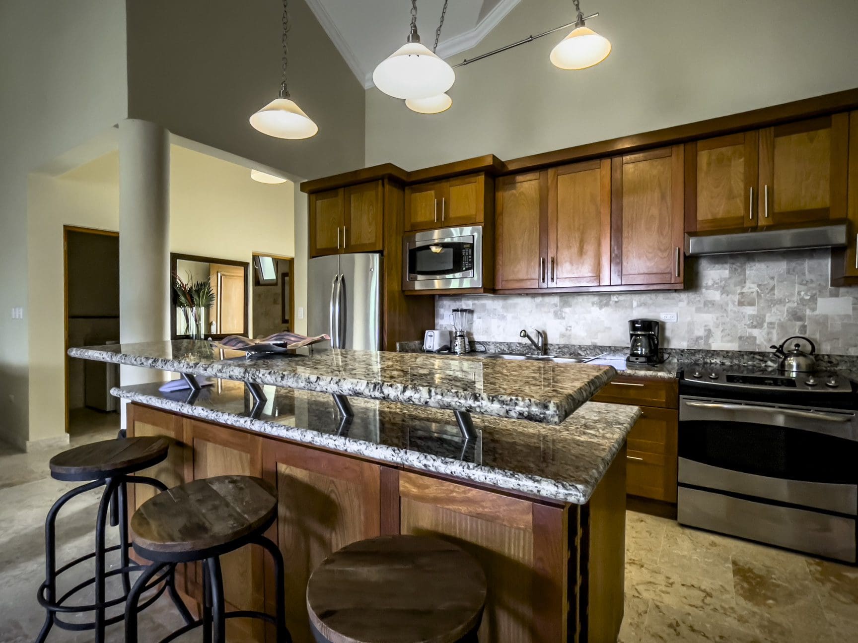 buyDRproperty Stunning 3 Bedroom Condo kitchen with wooden cabinets and a granite countertop island. Sosua Real Estate