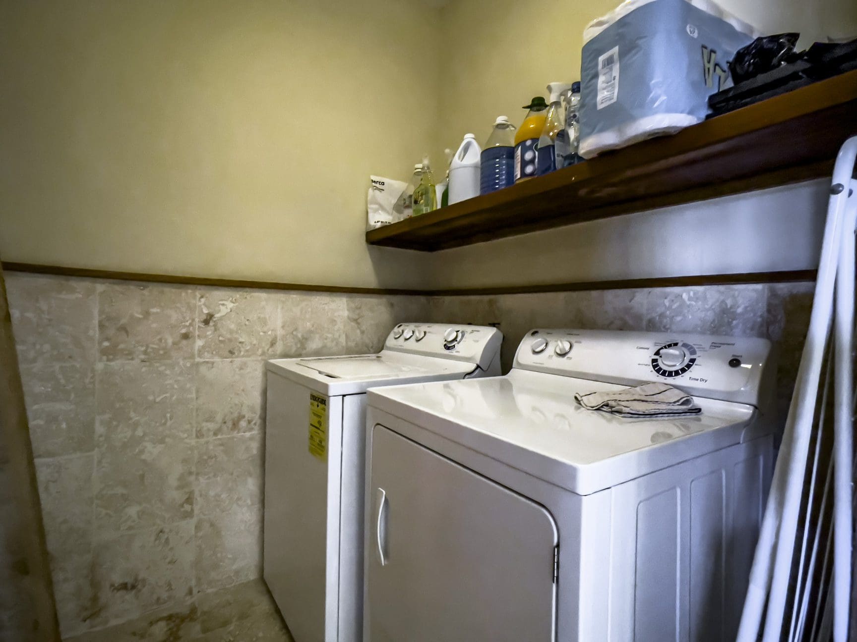 buyDRproperty Laundry room with a white washer and dryer, cleaning supplies on shelf. Sosua Real Estate
