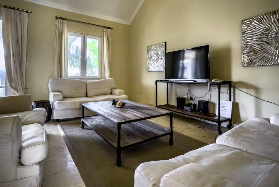 buyDRproperty Living room of a stunning 3 bedroom condo with white sofas, TV, and coffee table. Sosua Real Estate