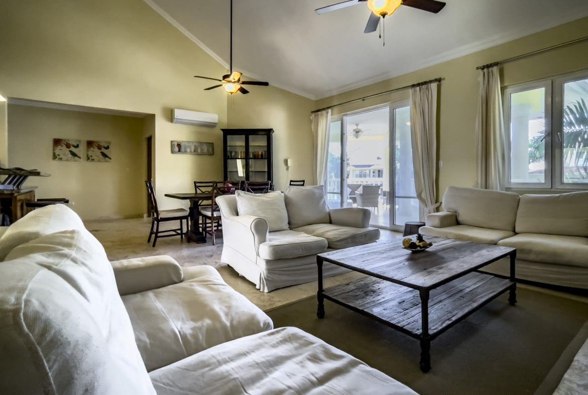 buyDRproperty Living room in a stunning 3 bedroom condo with white couches and rustic coffee table. Sosua Real Estate
