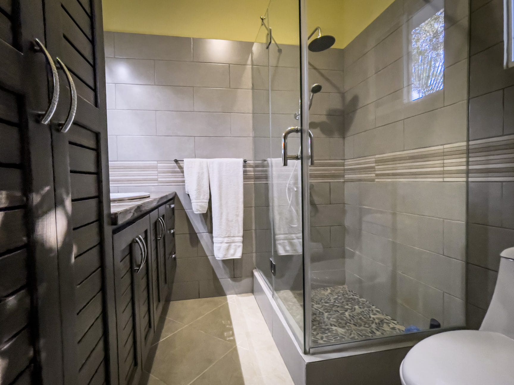 buyDRproperty Modern bathroom in a stunning 2 bedroom villa featuring a glass shower and dark wood vanity. Sosua Real Estate