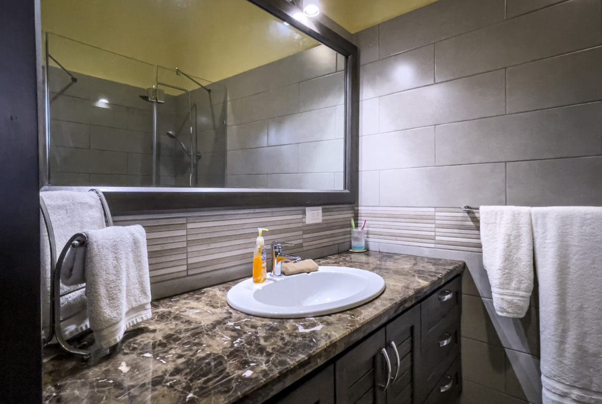 buyDRproperty Bathroom vanity with oval sink and mirror in a stunning 2 bedroom villa. Sosua Real Estate