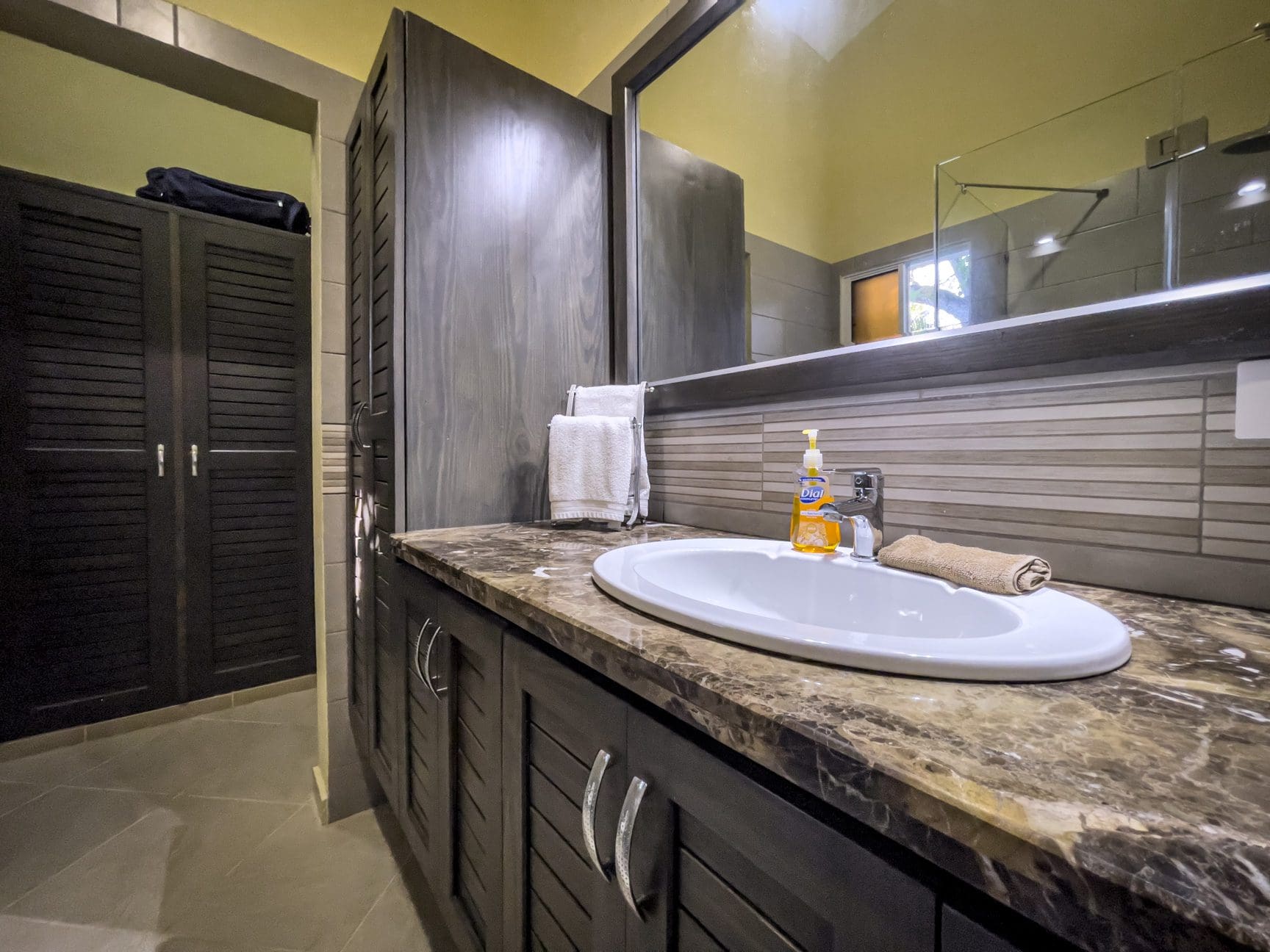 buyDRproperty Bathroom in a stunning 2 bedroom villa with dark wood cabinets, sink, and mirror. Sosua Real Estate