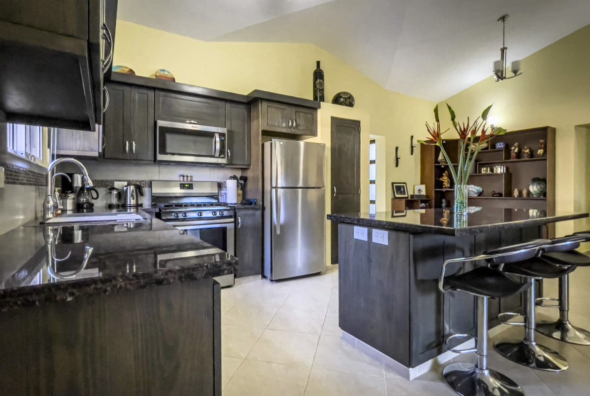 buyDRproperty Modern kitchen with dark cabinets and a breakfast bar in a Stunning 2 Bedroom Villa. Sosua Real Estate