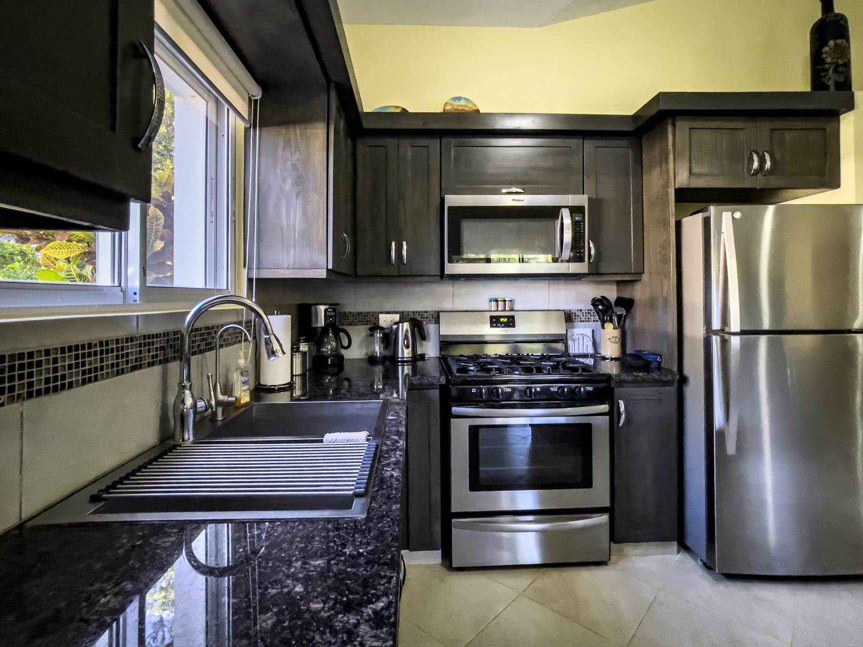 buyDRproperty Modern kitchen with dark cabinets and stainless steel appliances in a Stunning 2 Bedroom Villa. Sosua Real Estate