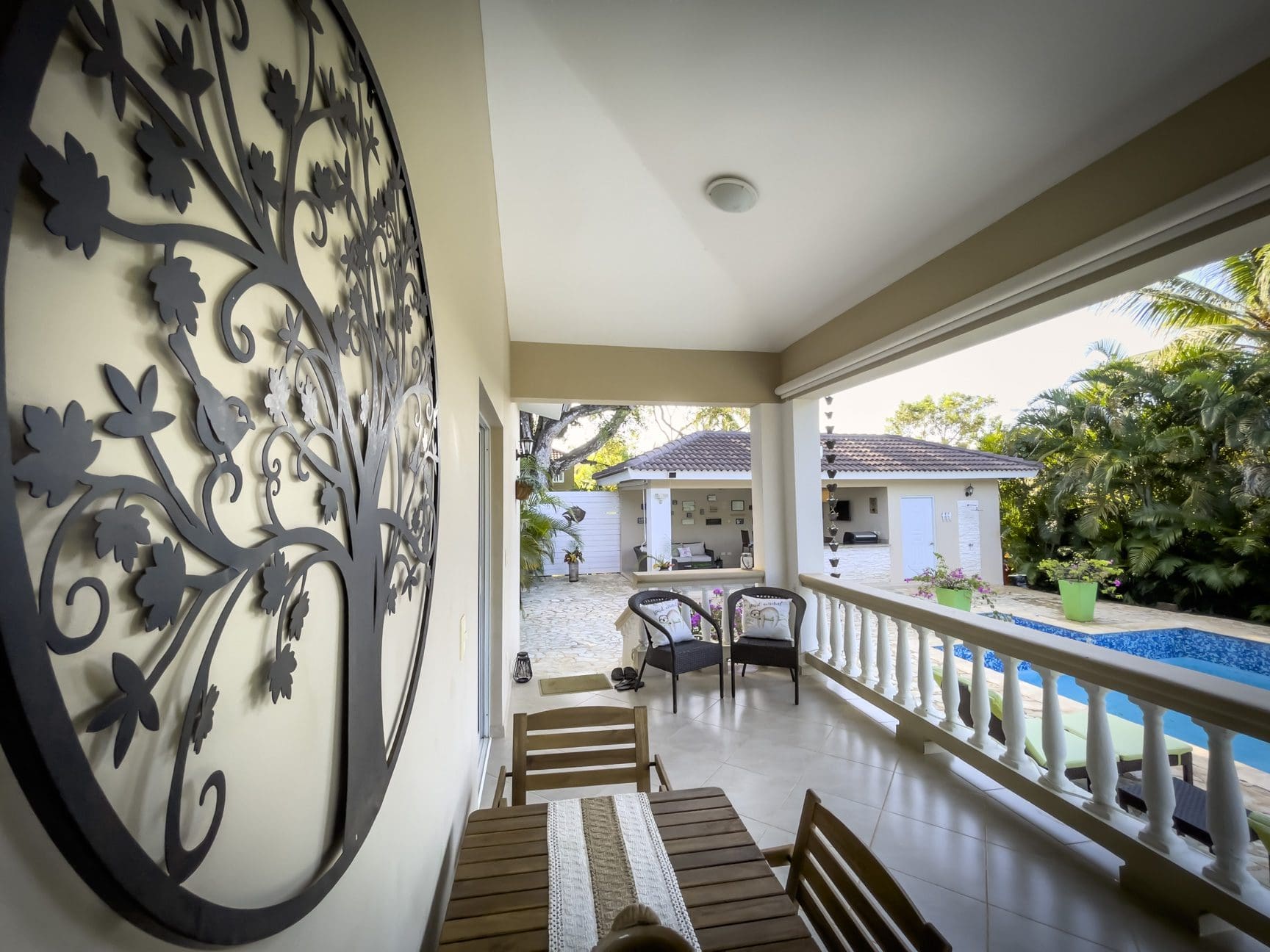 buyDRproperty Outdoor patio view of a stunning 2 bedroom villa with pool and decorative tree art. Sosua Real Estate