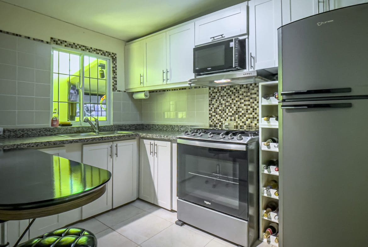 buyDRproperty Modern kitchen in a smart home for sale. Featuring white cabinets, stainless steel appliances, and a wine rack. Sosua Real Estate
