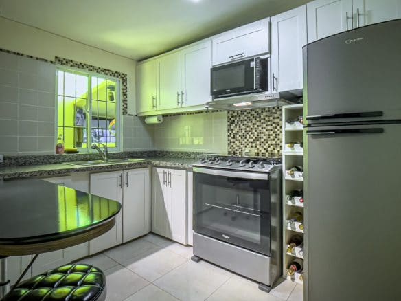 buyDRproperty Modern kitchen in a smart home for sale. Featuring white cabinets, stainless steel appliances, and a wine rack. Sosua Real Estate