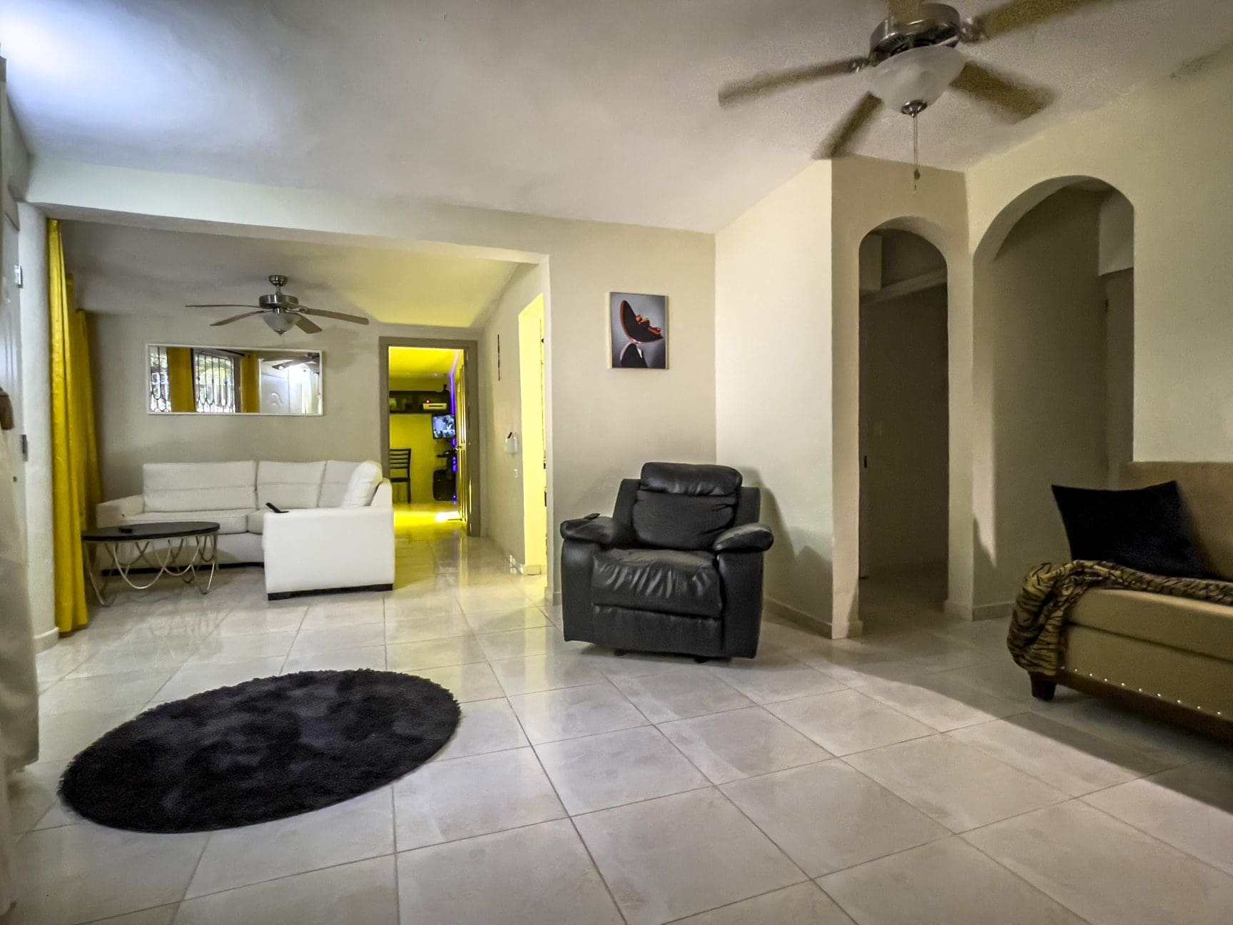 buyDRproperty Living room for sale in a smart home. Features include a black leather recliner and tiled floors. Sosua Real Estate
