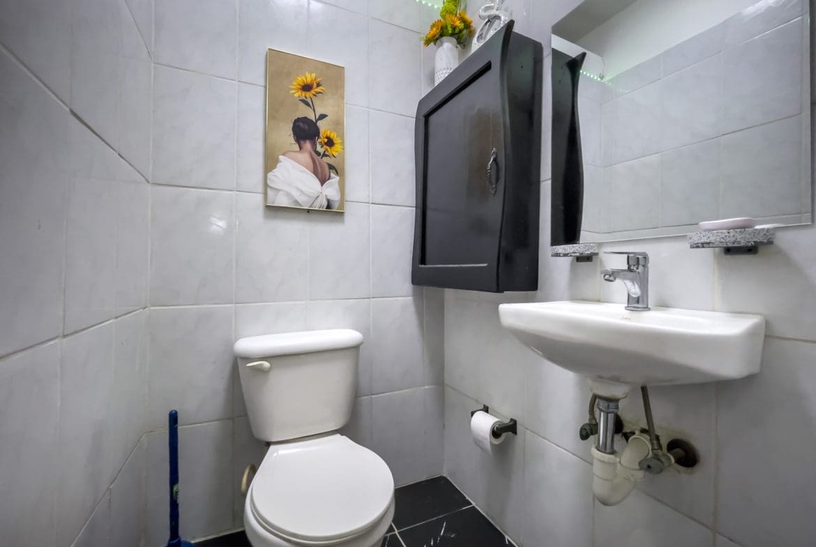 buyDRproperty Small bathroom with a toilet, sink, and black cabinet. For Sale! Smart Home. Sosua Real Estate