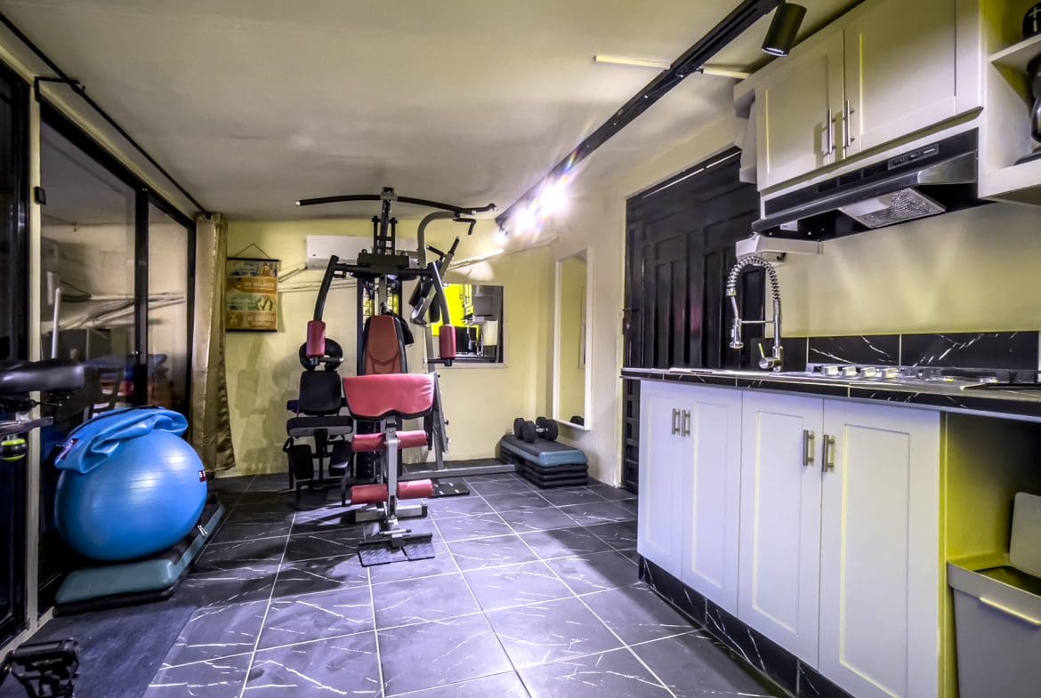 buyDRproperty Home gym with exercise equipment and kitchen, part of a "For Sale! Smart Home". Sosua Real Estate