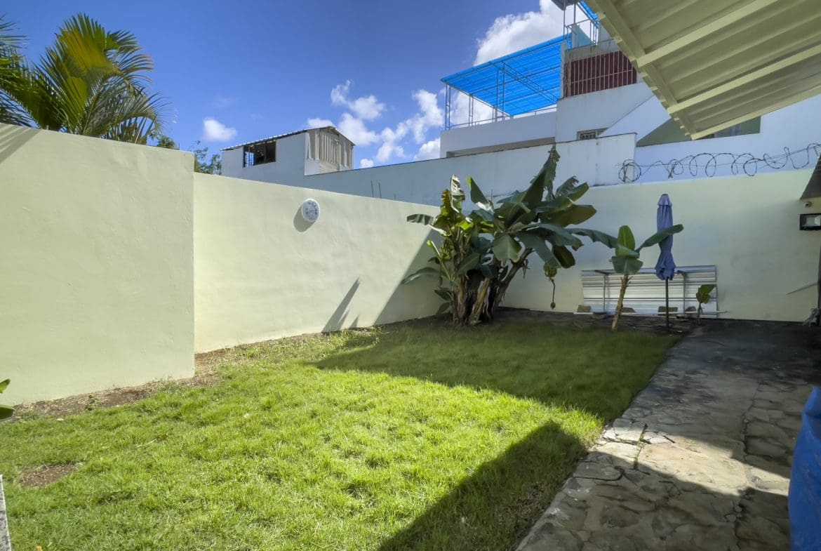 buyDRproperty Backyard with green grass, banana trees, and a blue sky. For Sale! Sosua Real Estate