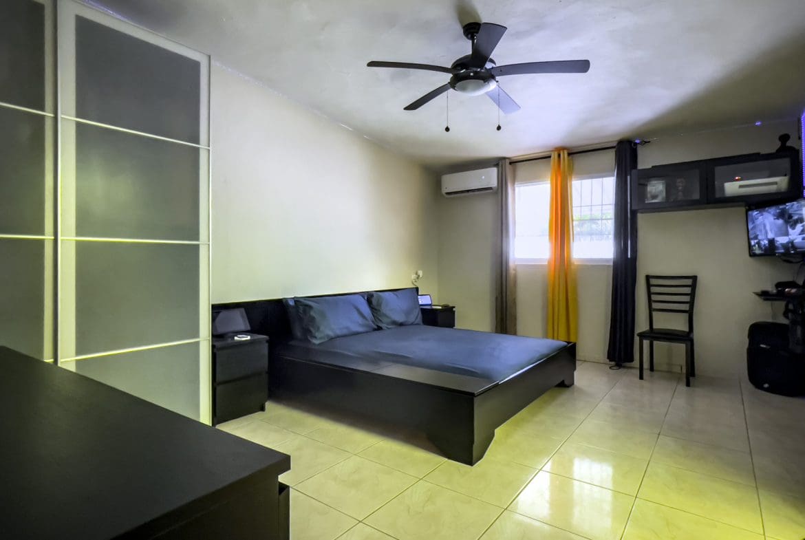 buyDRproperty Bedroom in a For Sale! Smart Home, featuring a bed, nightstand, and ceiling fan. Sosua Real Estate