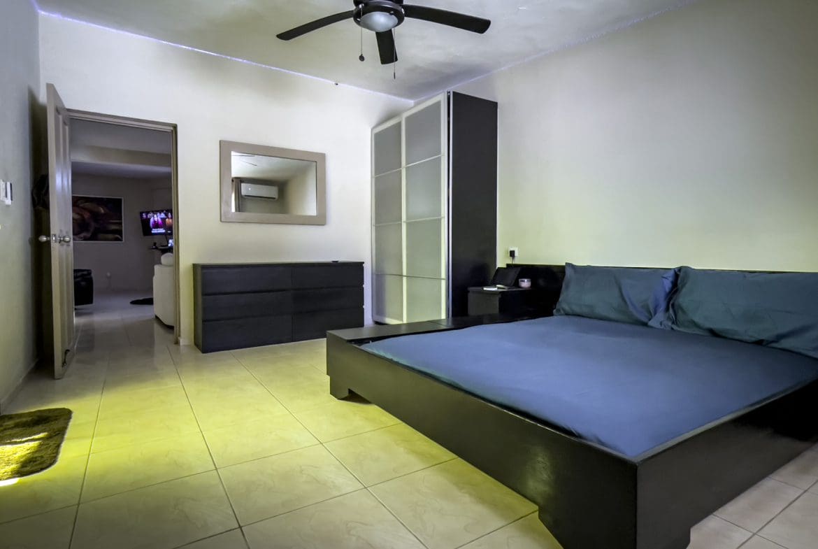 buyDRproperty Modern bedroom with a dark bed frame and blue bedding. For Sale! Smart Home. Sosua Real Estate