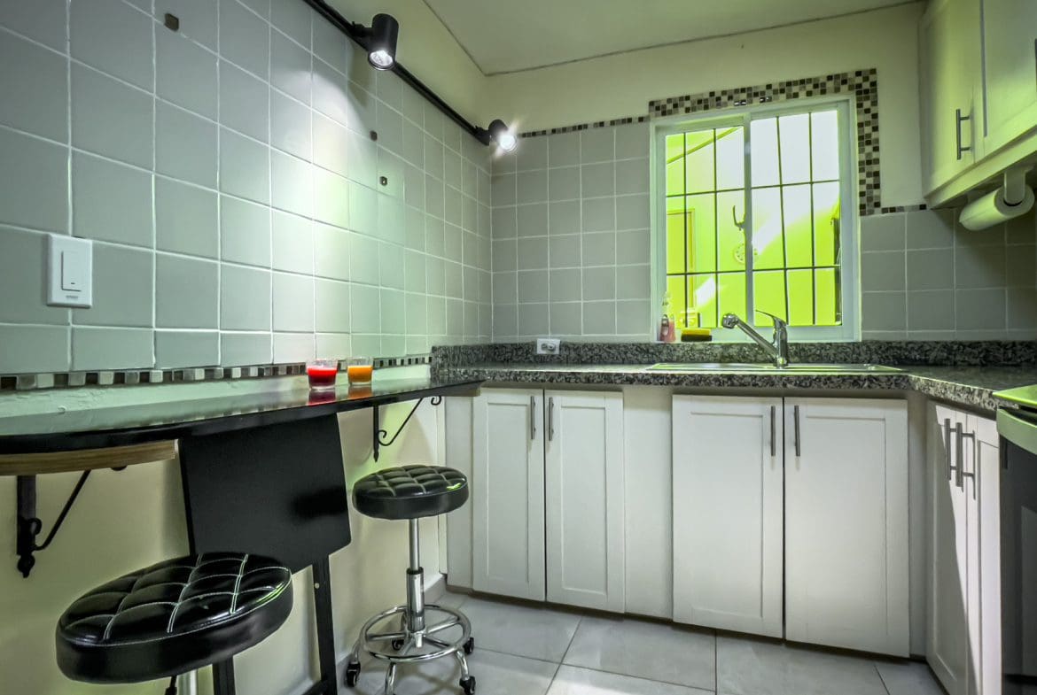 buyDRproperty Modern kitchen with white cabinets and a bar, perfect for a smart home for sale. Sosua Real Estate
