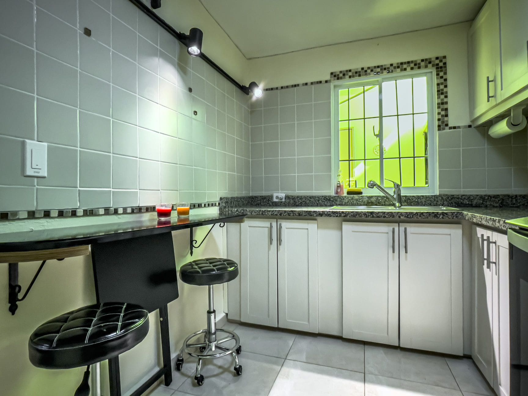 buyDRproperty Modern kitchen with white cabinets and a bar, perfect for a smart home for sale. Sosua Real Estate