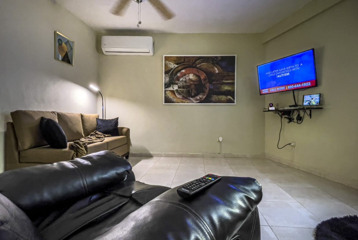 buyDRproperty Living room with TV showing an autism awareness ad. For Sale! Smart Home. Sosua Real Estate