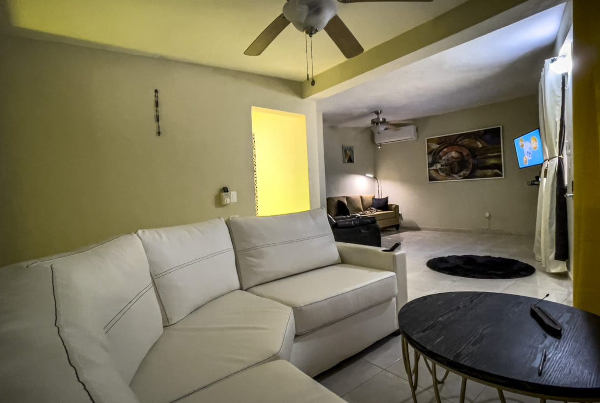 buyDRproperty Living room with white sectional sofa and a smart TV in a For Sale! Smart Home. Sosua Real Estate