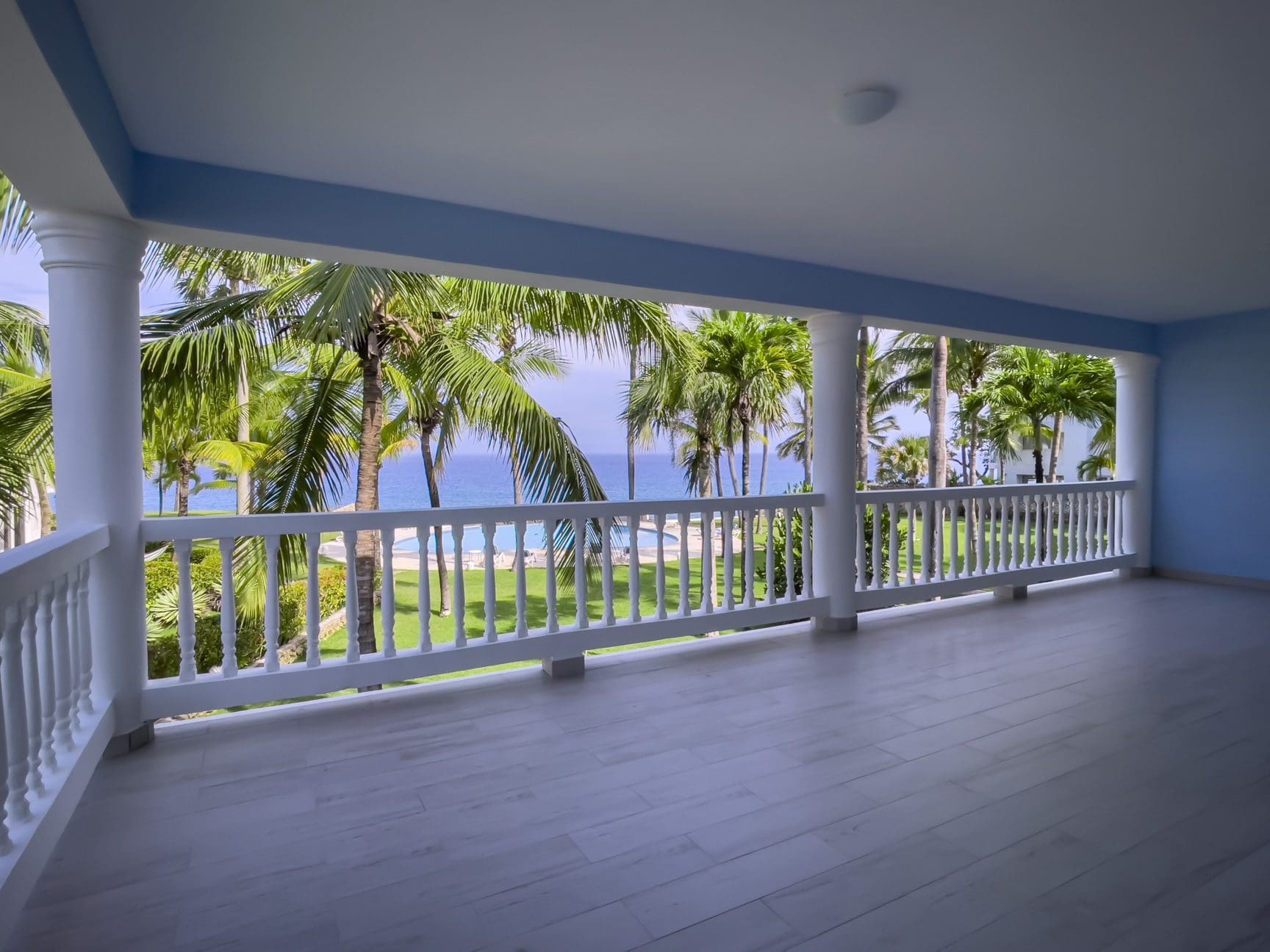 buyDRproperty Ocean view from a balcony of an oceanfront 2-bedroom condo with palm trees and ocean in the background. Sosua Real Estate
