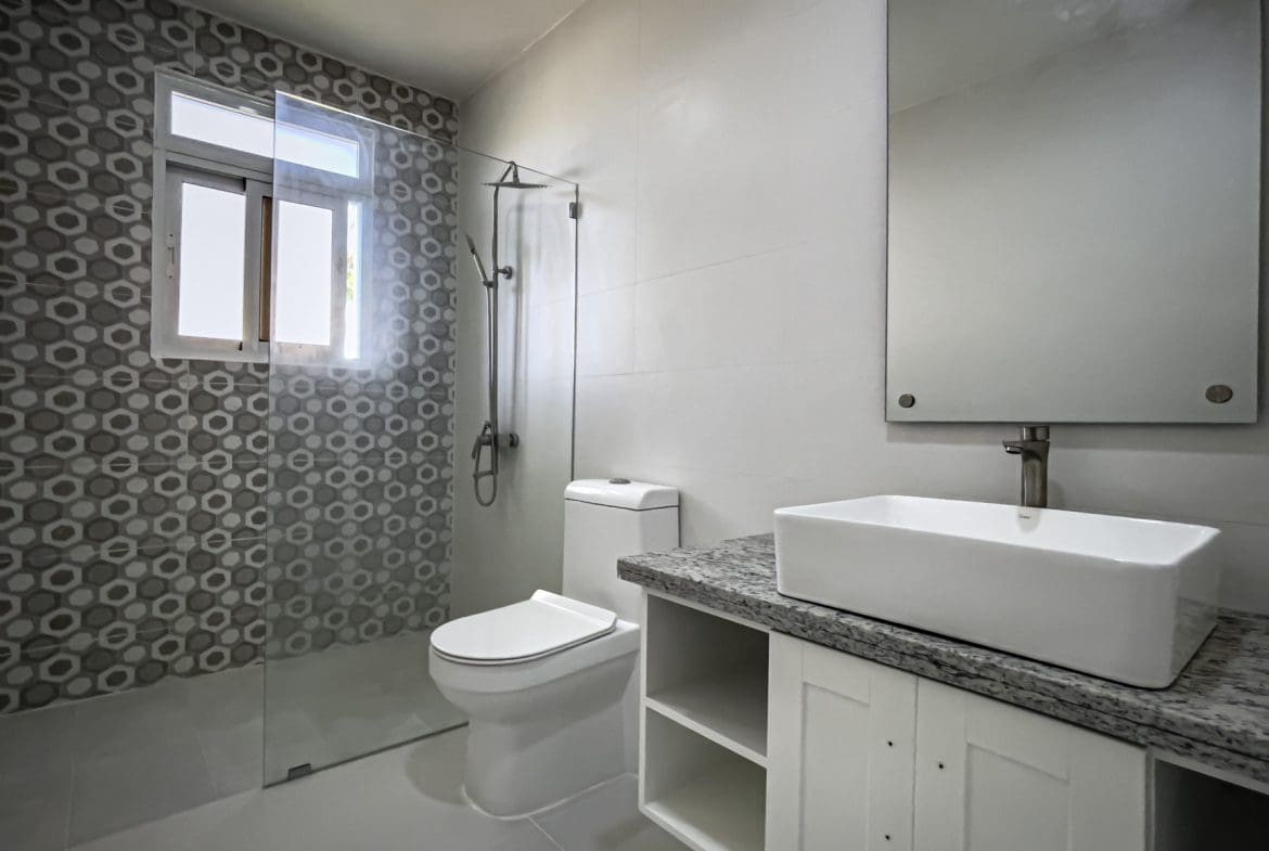 buyDRproperty Modern bathroom with white fixtures, shower, and geometric tile design. Sosua Real Estate