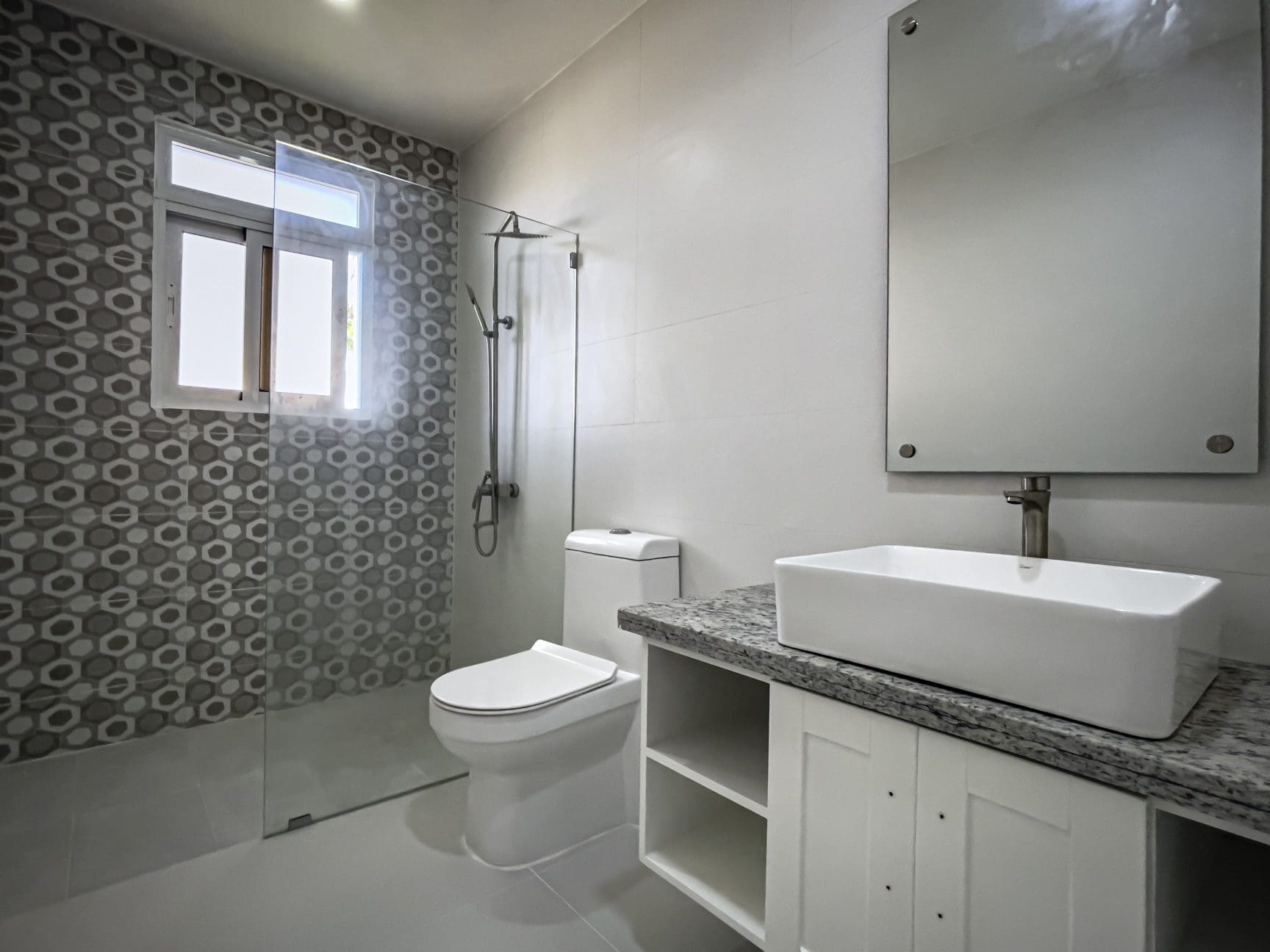 buyDRproperty Modern bathroom with white fixtures, shower, and geometric tile design. Sosua Real Estate