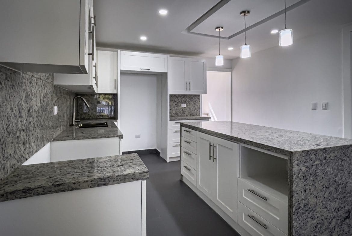 buyDRproperty Modern kitchen with white cabinets and granite countertops. Sosua Real Estate
