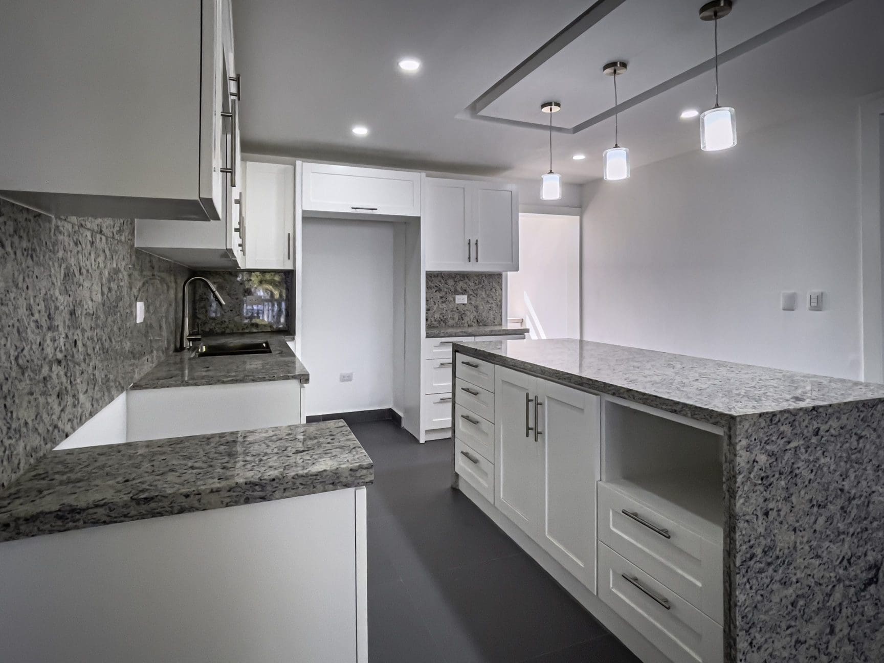 buyDRproperty Modern kitchen with white cabinets and granite countertops. Sosua Real Estate