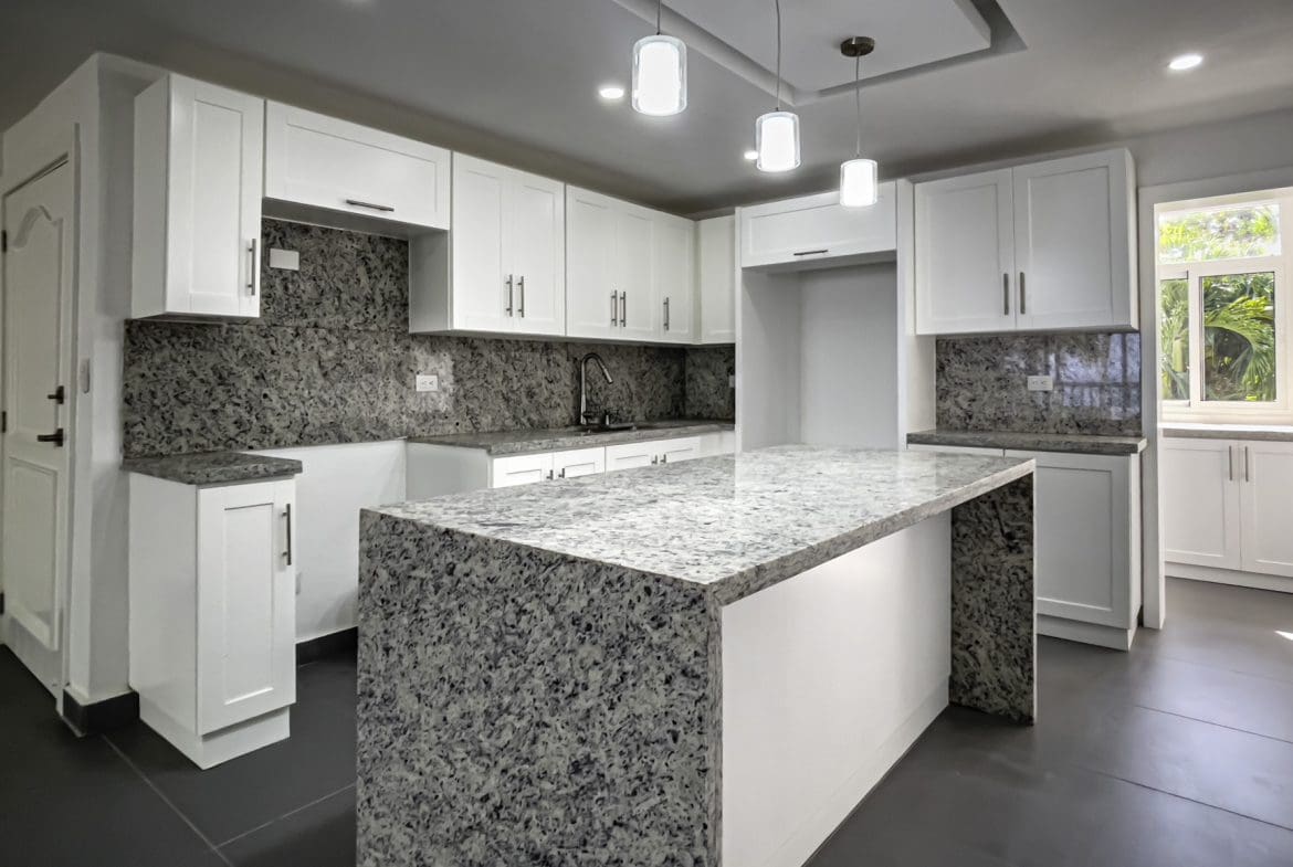buyDRproperty Modern kitchen with white cabinets, granite countertops, and island. Sosua Real Estate