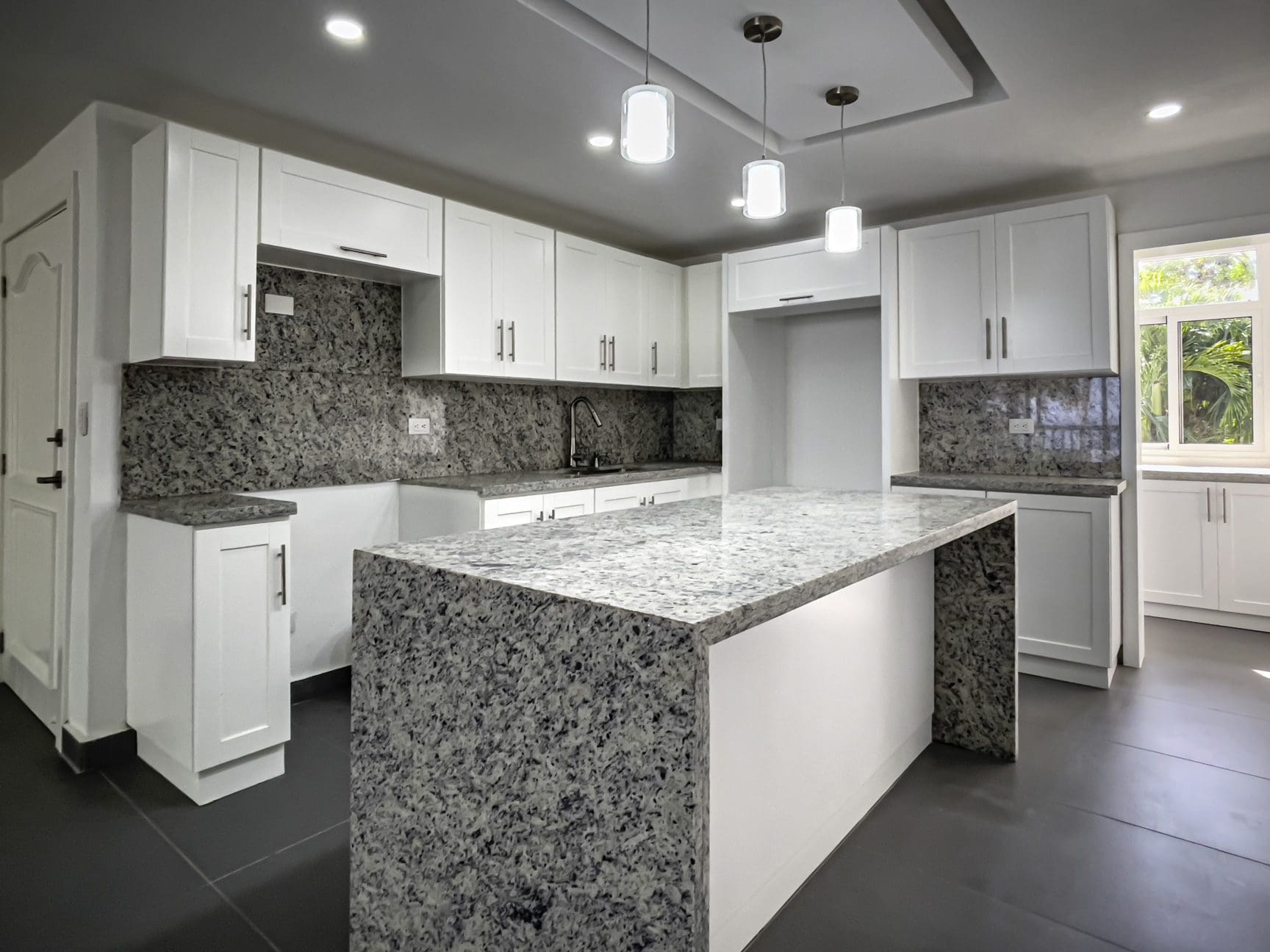 buyDRproperty Modern kitchen with white cabinets, granite countertops, and island. Sosua Real Estate