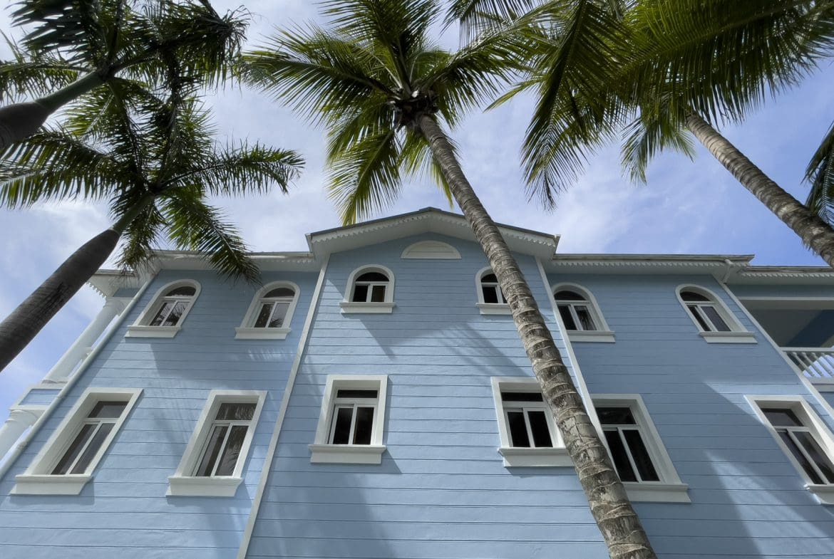buyDRproperty Blue building with white trim and palm trees, potentially oceanfront 2 bedroom condos. Sosua Real Estate