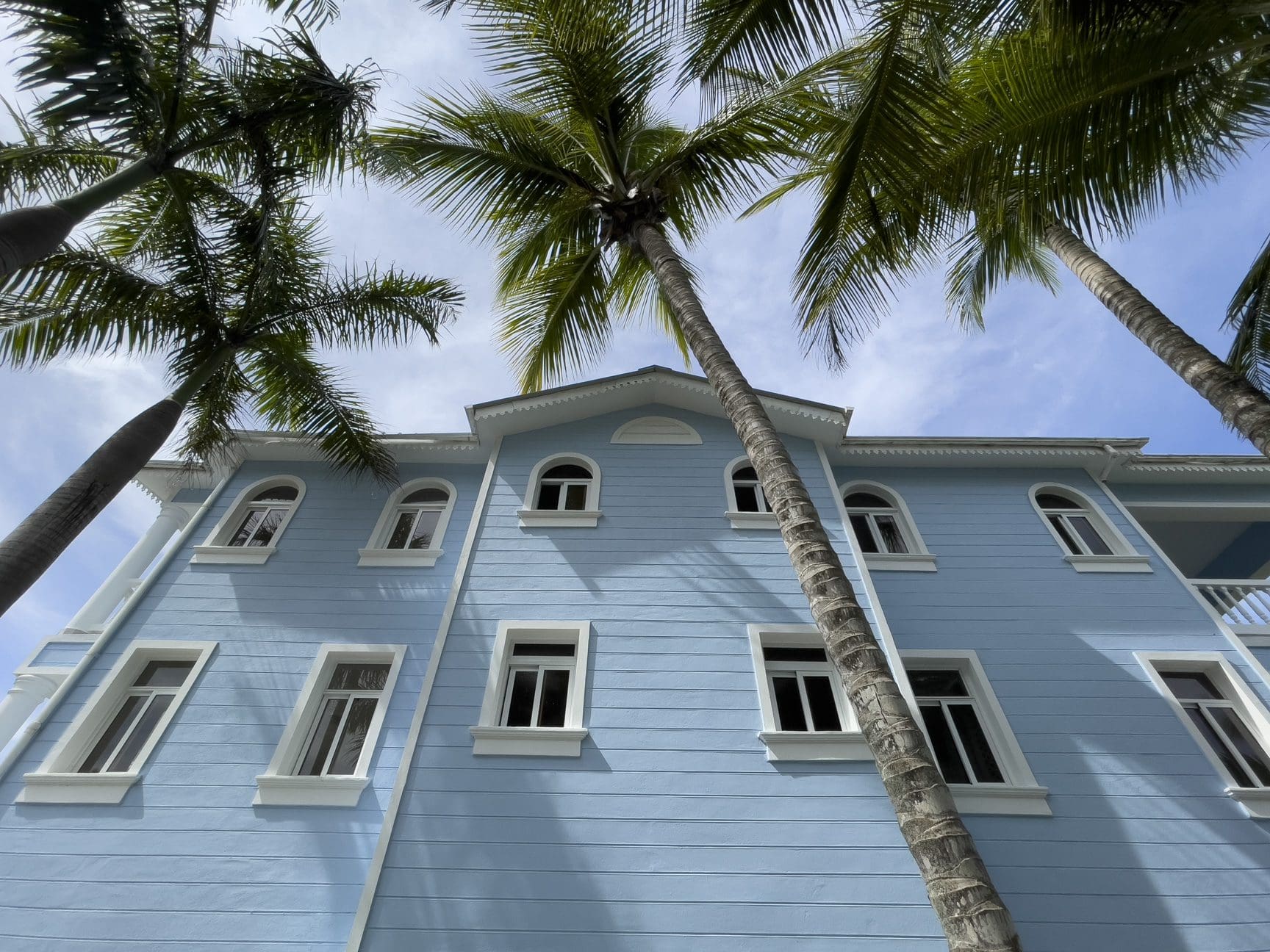 buyDRproperty Blue building with white trim and palm trees, potentially oceanfront 2 bedroom condos. Sosua Real Estate
