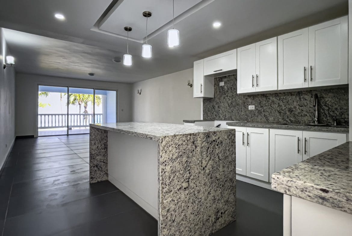 buyDRproperty Modern kitchen in oceanfront 2 bedroom condo. Granite countertops, white cabinets, and ocean view. Sosua Real Estate