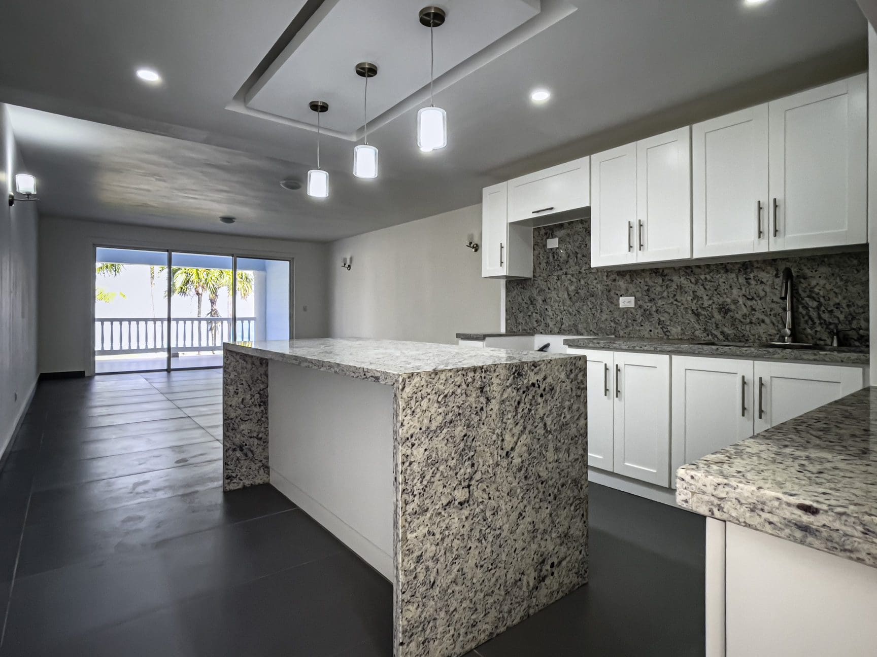 buyDRproperty Modern kitchen in oceanfront 2 bedroom condo. Granite countertops, white cabinets, and ocean view. Sosua Real Estate