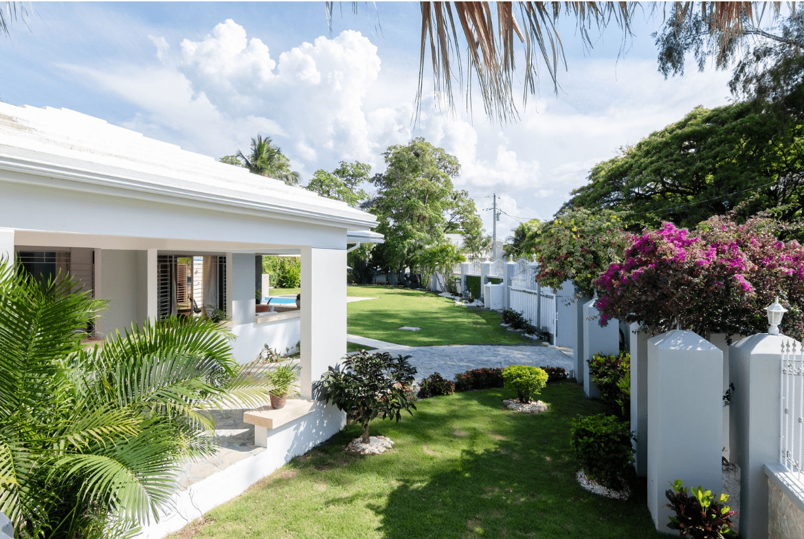 buyDRproperty Gorgeous 5 Bedroom Villa exterior with lush landscaping and green lawn Sosua Real Estate