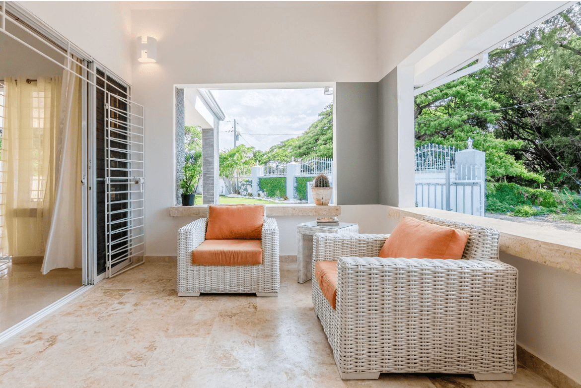 buyDRproperty Outdoor seating area with white woven chairs and orange cushions at a gorgeous 5 bedroom villa. Sosua Real Estate