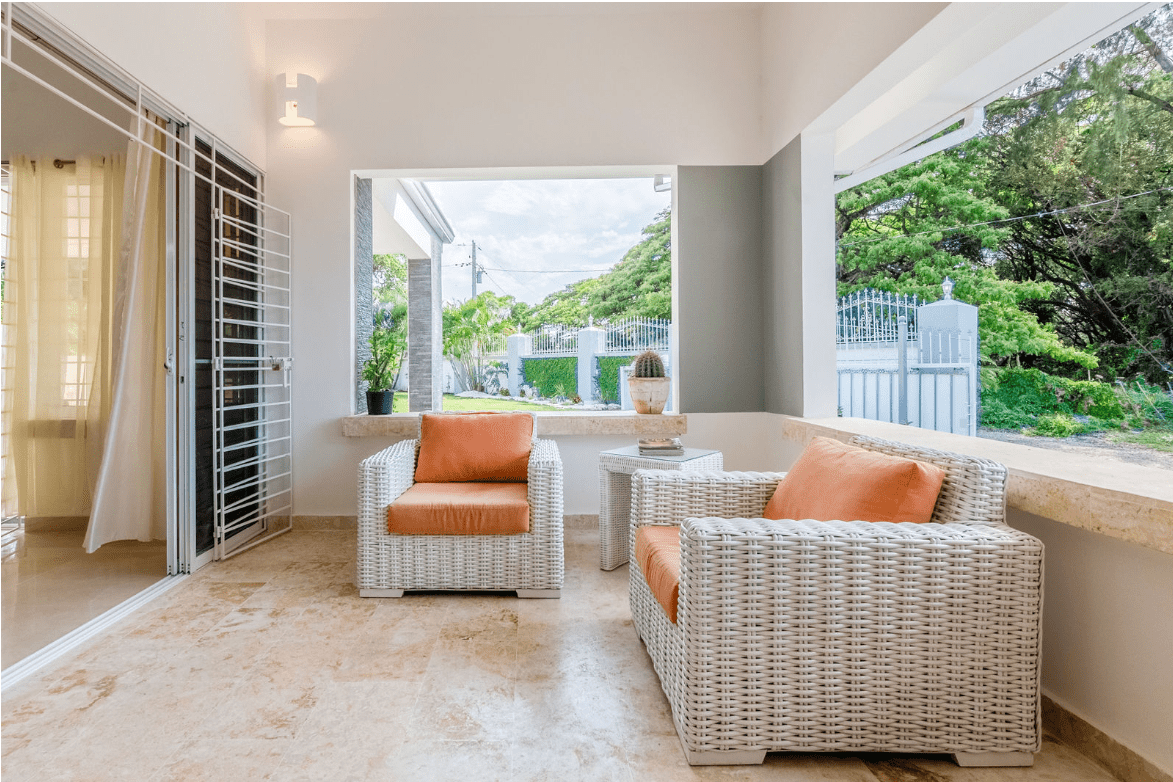 buyDRproperty Outdoor seating area with white woven chairs and orange cushions at a gorgeous 5 bedroom villa. Sosua Real Estate