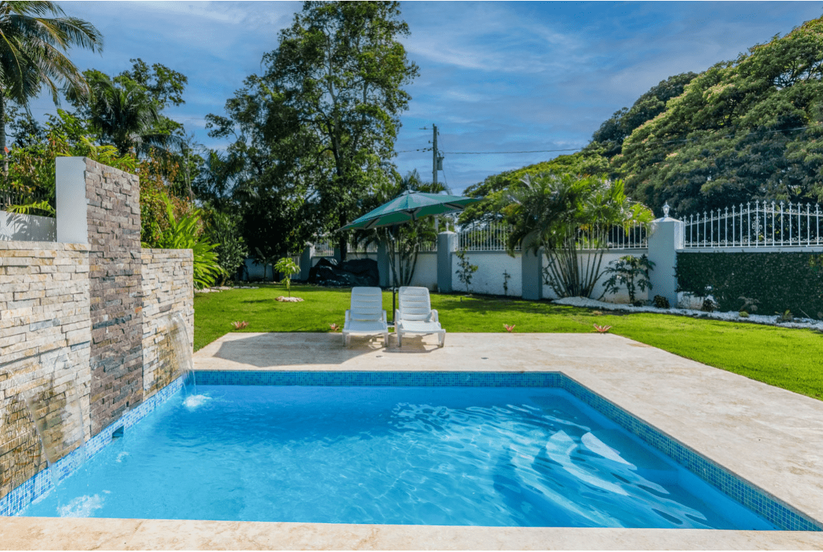 buyDRproperty Swimming pool at a gorgeous 5 bedroom villa. Outdoor space with lounge chairs and umbrella. Sosua Real Estate