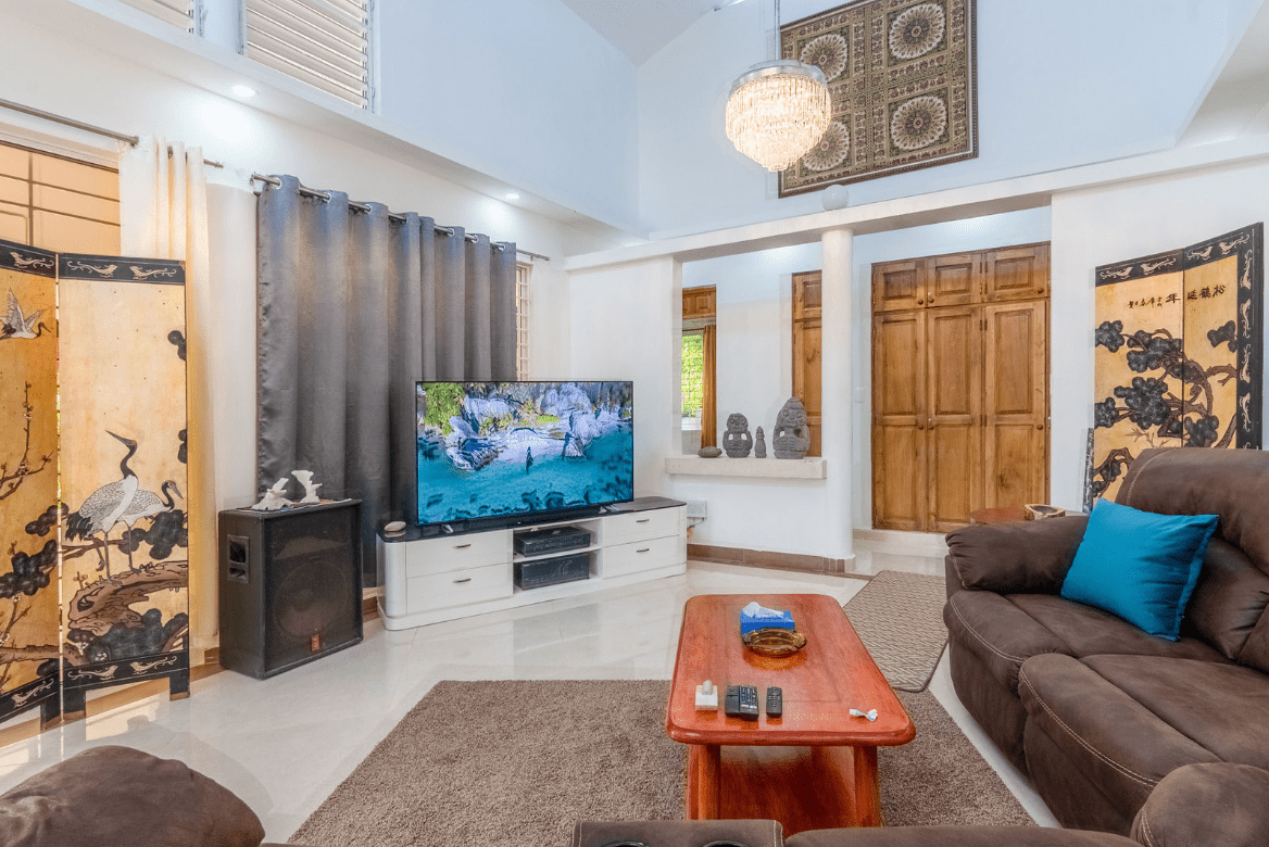 buyDRproperty Living room with a large TV, brown sofa, and decorative screens in a Gorgeous 5 Bedroom Villa. Sosua Real Estate