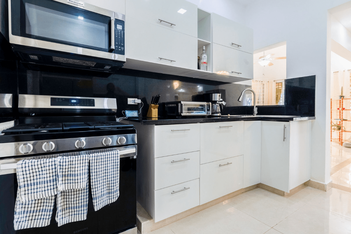 buyDRproperty Modern kitchen with white cabinets, stainless steel appliances, and a gas stove in a gorgeous 5 bedroom villa. Sosua Real Estate