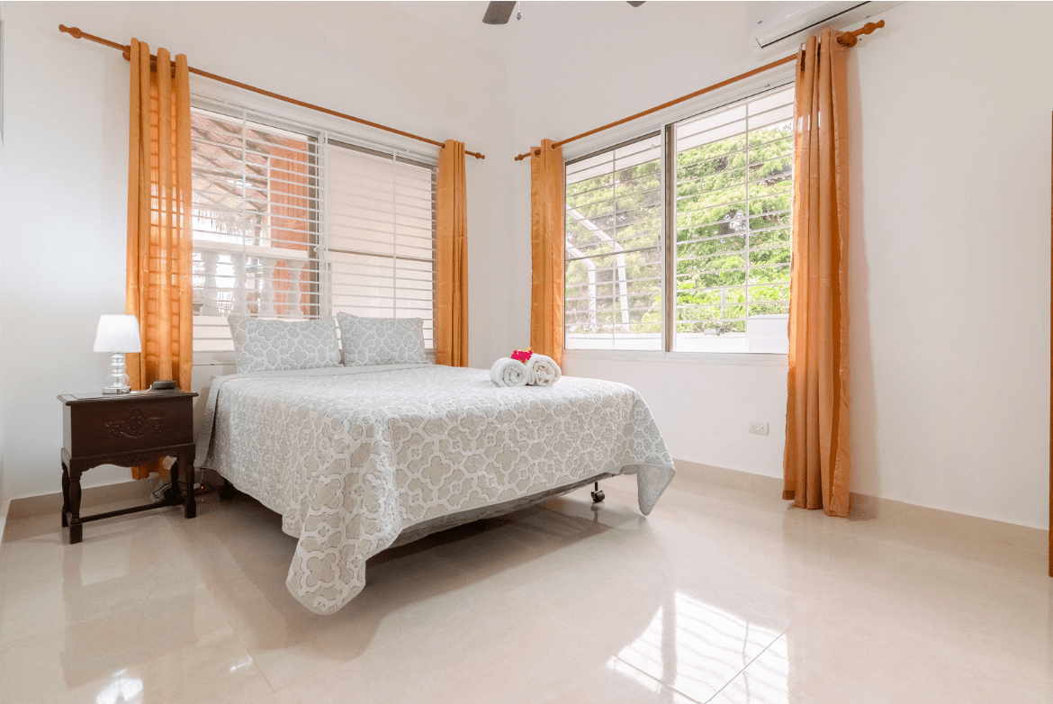 buyDRproperty Bedroom in a Gorgeous 5 Bedroom Villa with bed, pillows, and floral blanket Sosua Real Estate