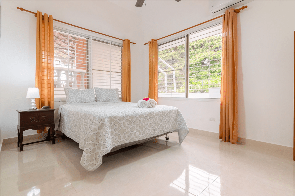 buyDRproperty Bedroom in a Gorgeous 5 Bedroom Villa with bed, pillows, and floral blanket Sosua Real Estate